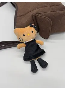 Detail of Hello Kitty plush charm with black velvet dress and pearl necklace on handbag