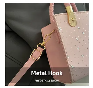 Detailed shot of pink crossbody bag with star pattern, woven handle and gold metal hooks