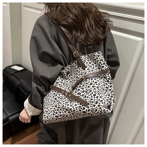 Detail view of leopard print tote bag with brown leather straps and gold metal eyelets