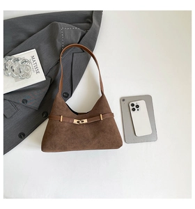Close-up of deep brown suede tote with a golden buckle and modern office essentials