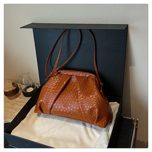 Detail of a brown woven shell bag inside a luxury gift box with elegant styling