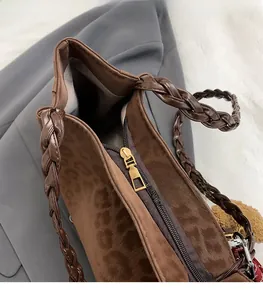 Dettaglio della borsa leopardata con zip dorata e manico in pelle intrecciata scura