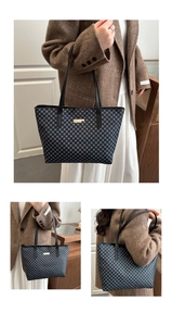 Detail of blue and black geometric tote bag with gold metal plaque and thin shoulder strap
