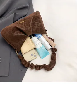 Detail of leopard print shoulder bag showing spacious interior with wallet and phone
