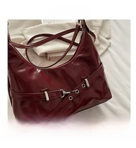 Detail view of burgundy patent leather bag with silver metal buckle and strap details