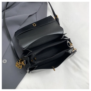 Detail view of the black leather bag interior showing three main compartments and gold lock