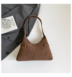 Macro detail of dark brown suede hobo bag with leather straps and gold buckle