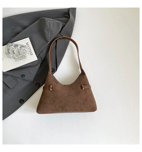 Macro detail of dark brown suede tote bag with leather straps and gold hardware