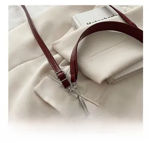 Detailed close-up of wine red leather strap with silver adjustable metal buckle and stitching