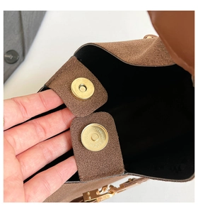 Detail of magnetic gold buckles on brown suede tote bag with black interior lining