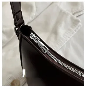 Close-up of smooth silver zipper detail on dark brown vintage underarm shoulder bag