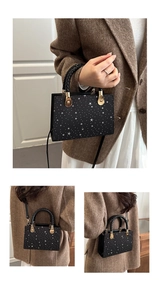 Detail of black mini crossbody bag with star pattern, woven handle and gold hardware