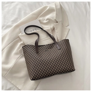 Close-up of vintage pattern tote bag with metal plaque on elegant white suit background
