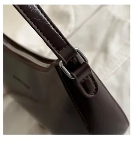 Close-up of silver metal rings and stitching on a dark brown vintage leather shoulder bag