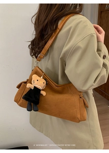 Detailed view of a vintage brown suede square crossbody bag with a plush character charm