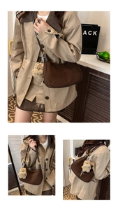 Detailed close-up of dark brown suede crescent bag with a cute plush bear pendant