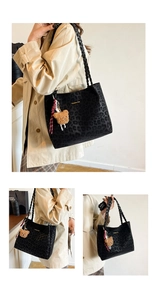 Detail of leopard print tote bag with woven straps and plush bear charm decoration