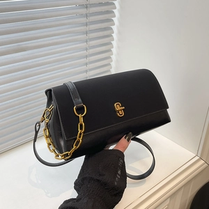 Classic black leather crossbody bag with golden lock and chain detail on white window sill