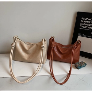 Detail of minimalist hobo bags in beige and brown with knotted straps and jacquard webbing