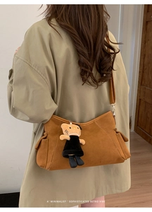 Detailed view of camel suede shoulder bag with retro vibes and cute cat plush pendant
