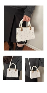 Three-way view of white star-patterned crossbody bag showing handle and gold hardware