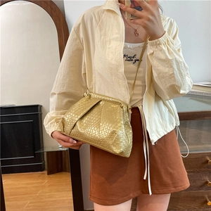 Golden woven cloud shell bag with minimalist texture and adjustable shoulder strap