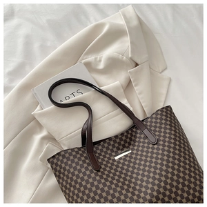 Close-up of deep brown tote bag with golden geometric clover pattern and leather straps