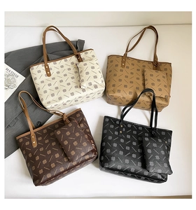 Flat lay of four monogram tote bags in white, beige, brown, and black colors