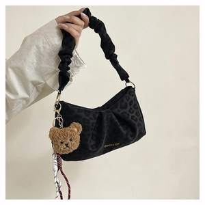 Detail of black leopard print pleated underarm bag with cute plush bear charm
