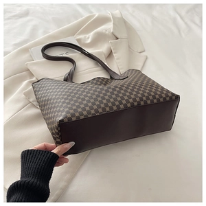 Detail of a large brown geometric tote bag on a white suit and bedding background