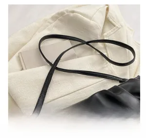 Detail of elegant black pleated cloud bag with slim leather strap and silver buckle closure