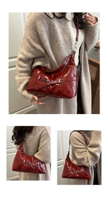 Close-up of a deep red patent leather underarm bag with silver buckle and adjustable strap