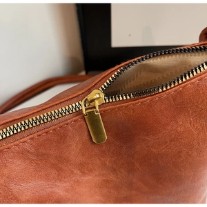 Detailed macro view of vintage brown leather texture and premium gold metal zipper closure