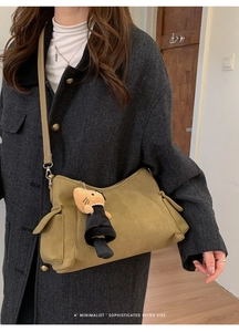 Detailed side view of an olive green retro crossbody bag featuring a cat doll pendant