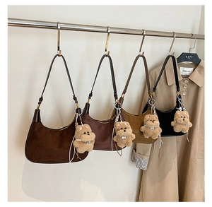 Detailed close-up of four colored suede hobo bags with cute plush bear charms on a rack