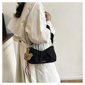 Leopard print underarm bag detail with plush bear charm on white trench coat