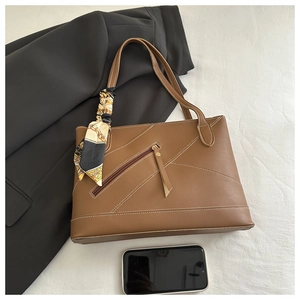 Brown leather tote bag featuring a diagonal zipper pocket and floral scarf handle detail