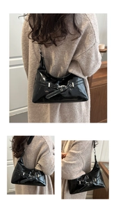Close-up of black glossy patent leather hobo bag with vintage buckle and metal eyelets