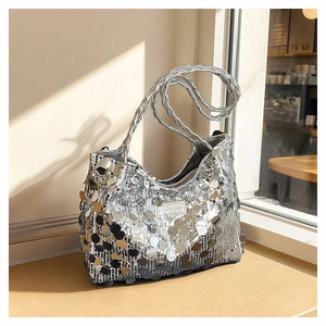 Macro detail of large silver sequins and a woven shoulder strap on a chic hobo bag