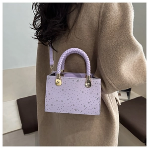 Detail of lavender star print crossbody bag with woven leather handle and gold hardware