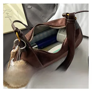 Spacious interior of dark brown suede cylinder bag with toiletries and bear charm