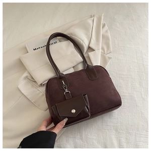 Close-up of dark brown suede shoulder bag set with small pouch on white blazer