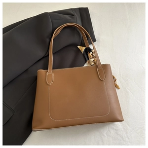Brown leather tote bag featuring contrast stitching and a decorative silk scarf