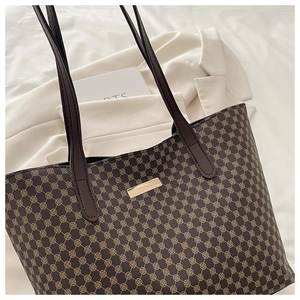 Detailed close-up of dark brown tote bag with golden geometric pattern and leather straps