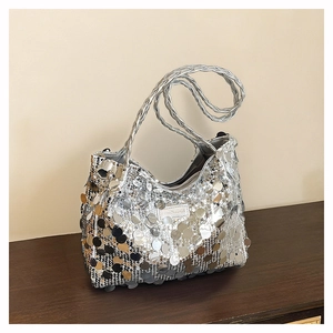 Detail of silver sequin shoulder bag with woven handle and fashion label on wood table