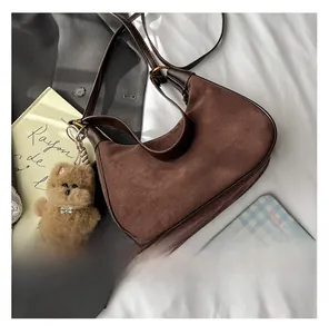 Flat lay of vintage coffee suede crescent shoulder bag with cute teddy bear charm