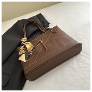 Detail of brown tote bag featuring white stitching and decorative vintage silk scarf