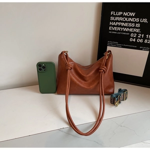 Brown leather tote bag featuring a knotted handle and a bohemian jacquard strap detail