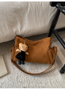 Detail of caramel suede shoulder bag with retro design and cute plush doll pendant