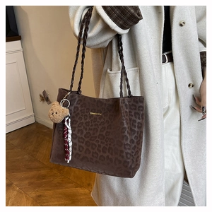 Dettaglio borsa shopper leopardata con ciondolo a orsetto e nastro su cappotto